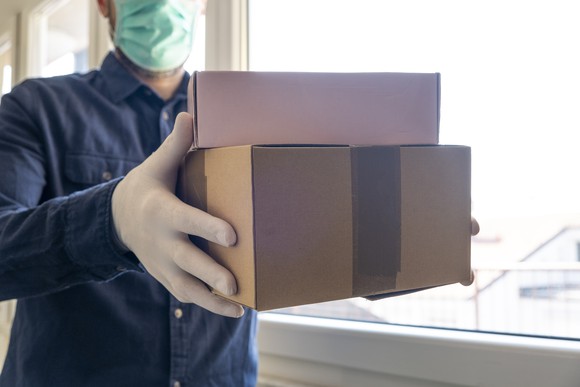 A man wearing a mask dropping off packages. 