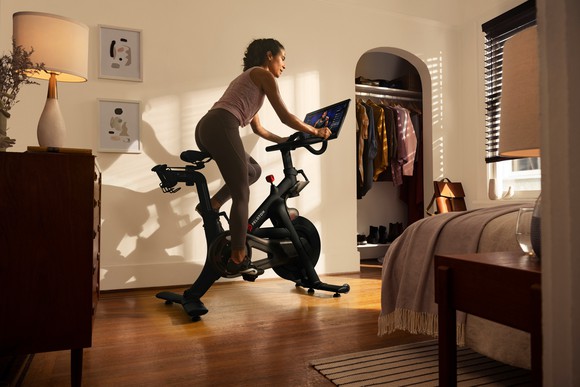 A woman riding a Peloton stationary bike in a bedroom. 