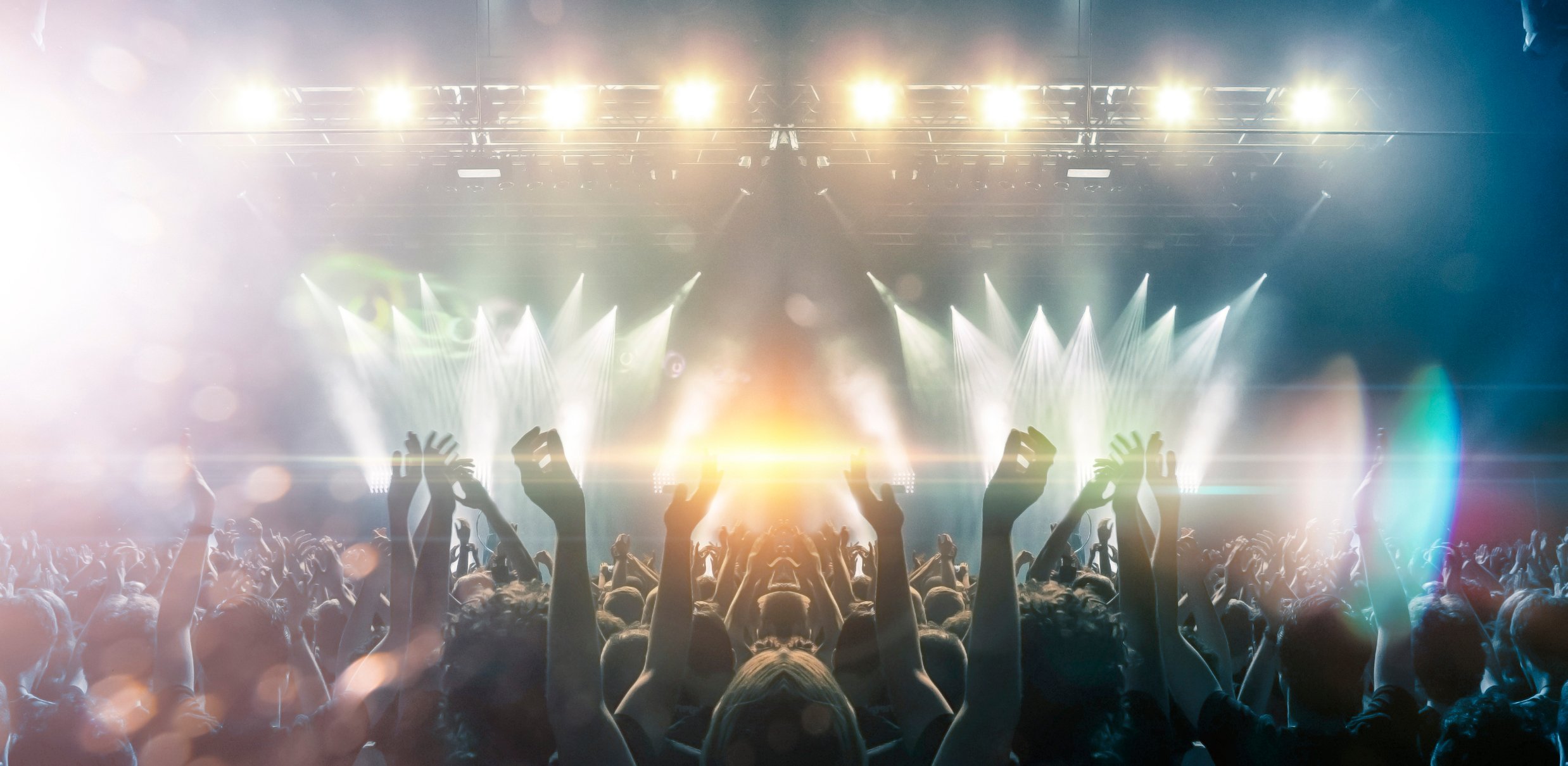 live concert crowd cheering in front of lights and stage
