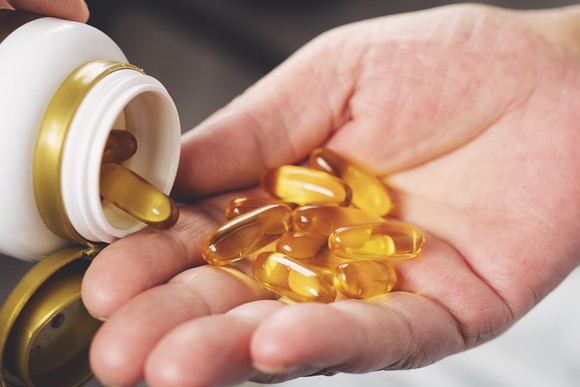 Woman pouring fish oil capsules into the palm of her hand