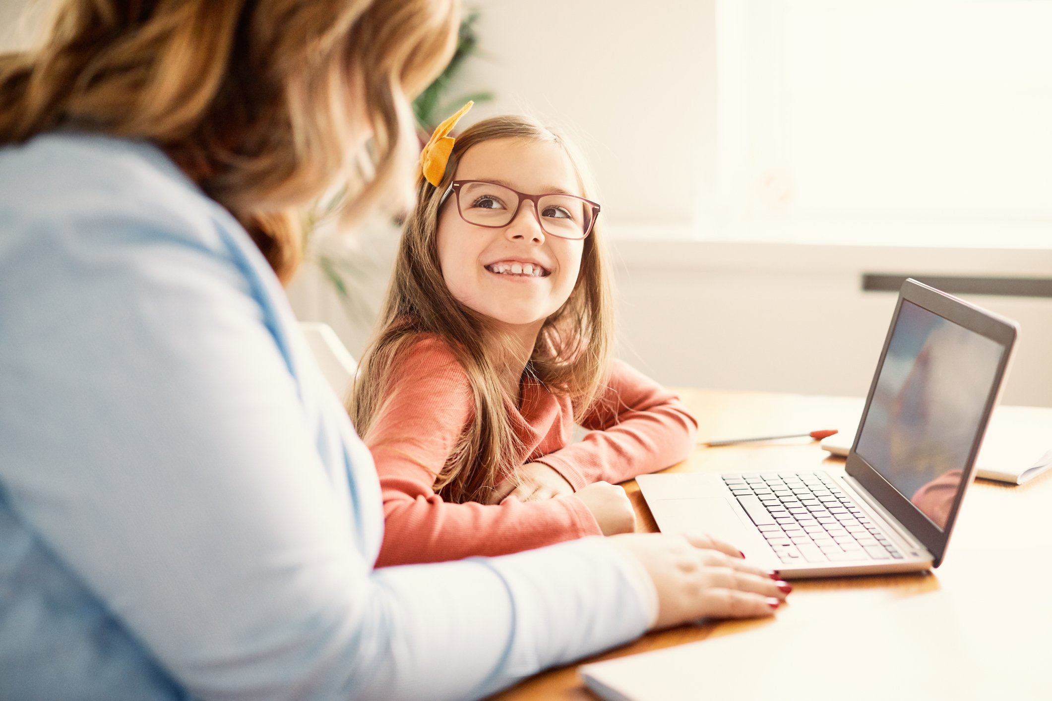 A mother and daughter work together on a laptop.