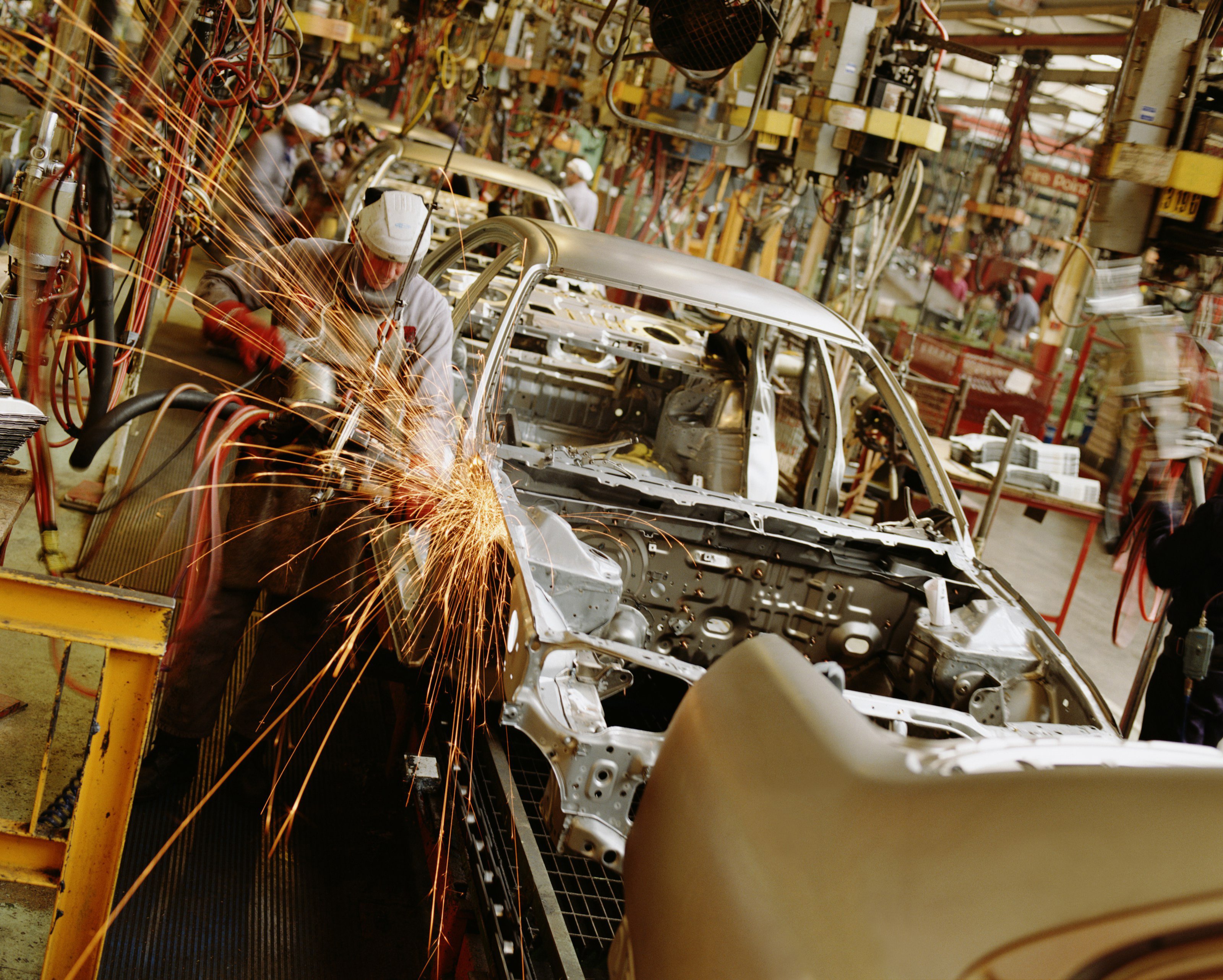 auto assembly line worker welding on auto frame