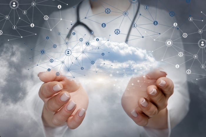 A doctor holding a cloud connected to digital data points. 