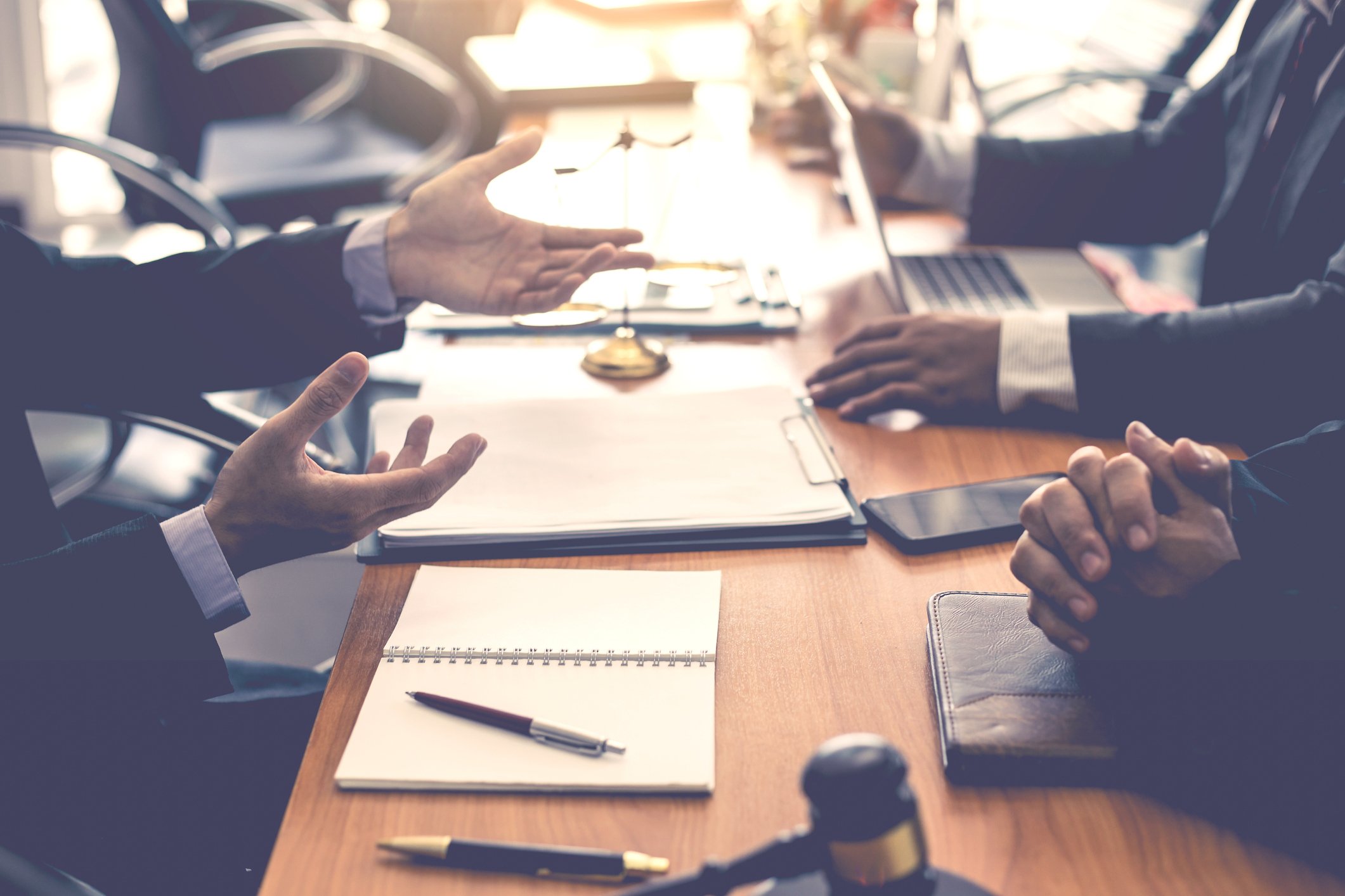 Business men gather around a meeting table.
