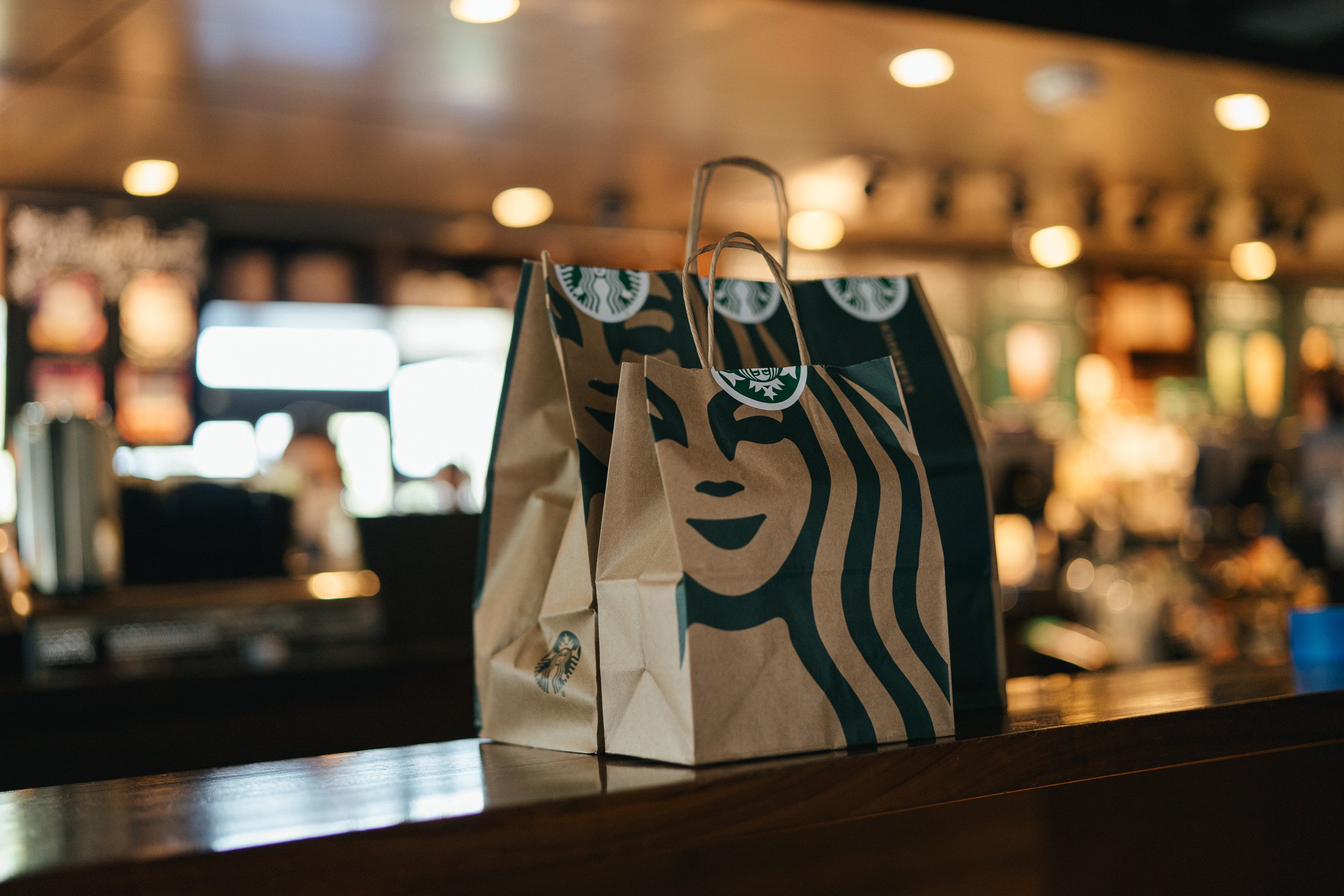 Two Starbucks bags wait on the store counter for pickup.