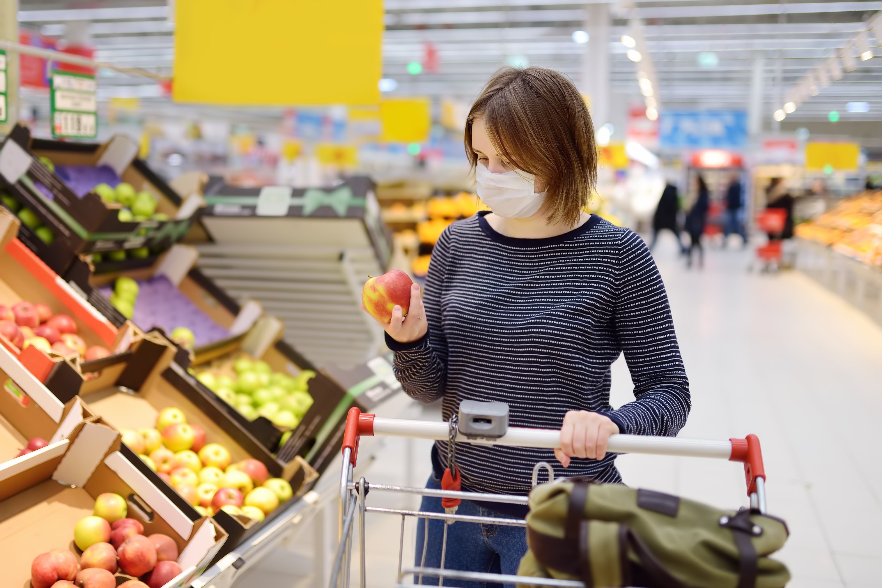 Woman wearing a surgical mask as she shops in a grocery store.