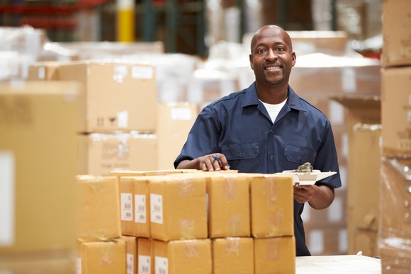 Man smiling while standing beside parcels in a warehouse
