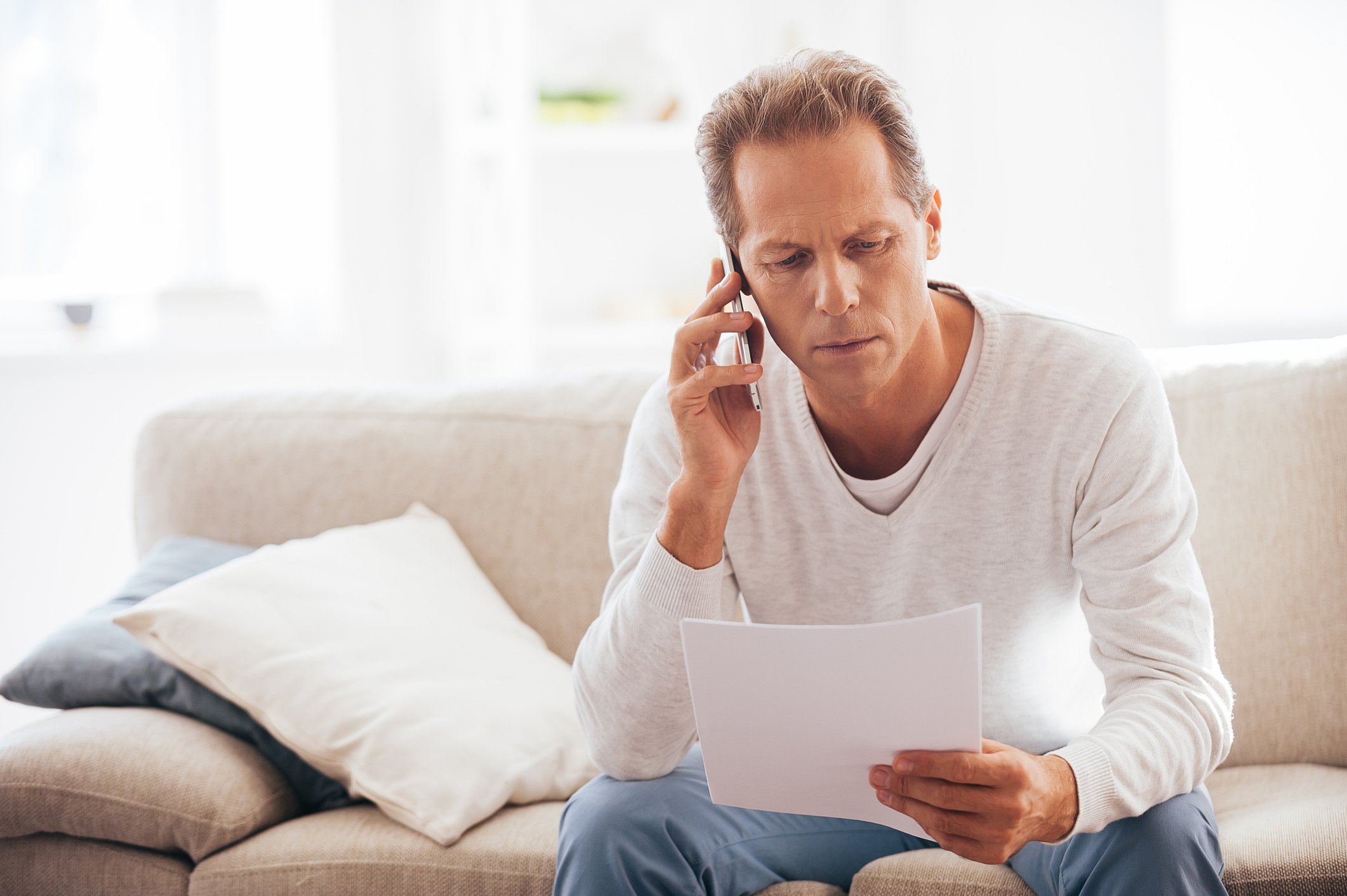 A man on the phone reviewing financial paperwork