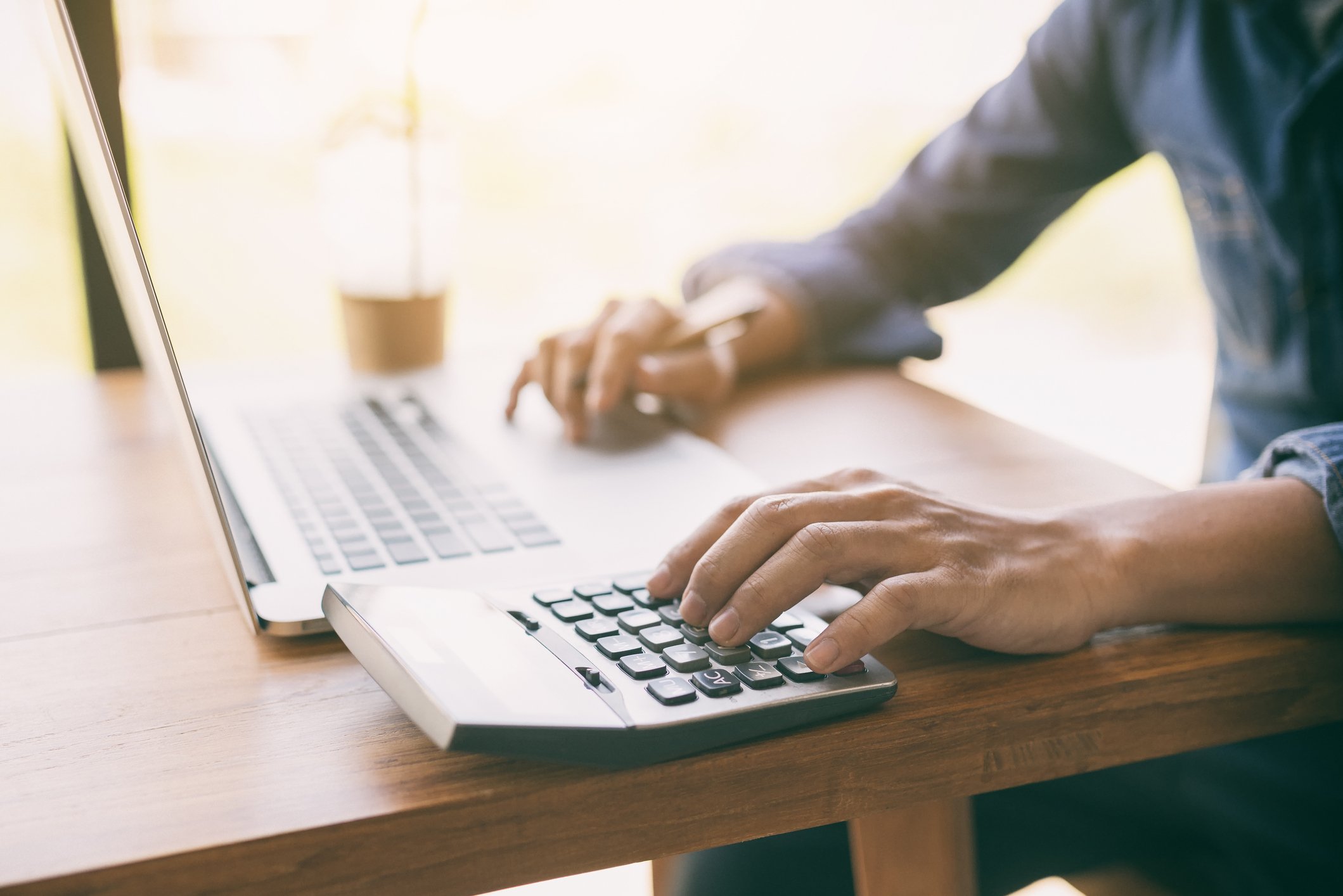 Man at laptop typing on calculator