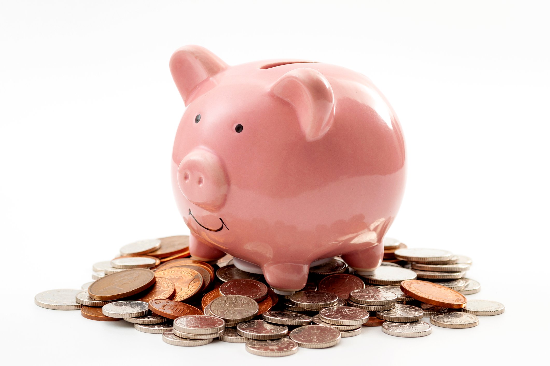 A piggy bank stands on a pile of small change.