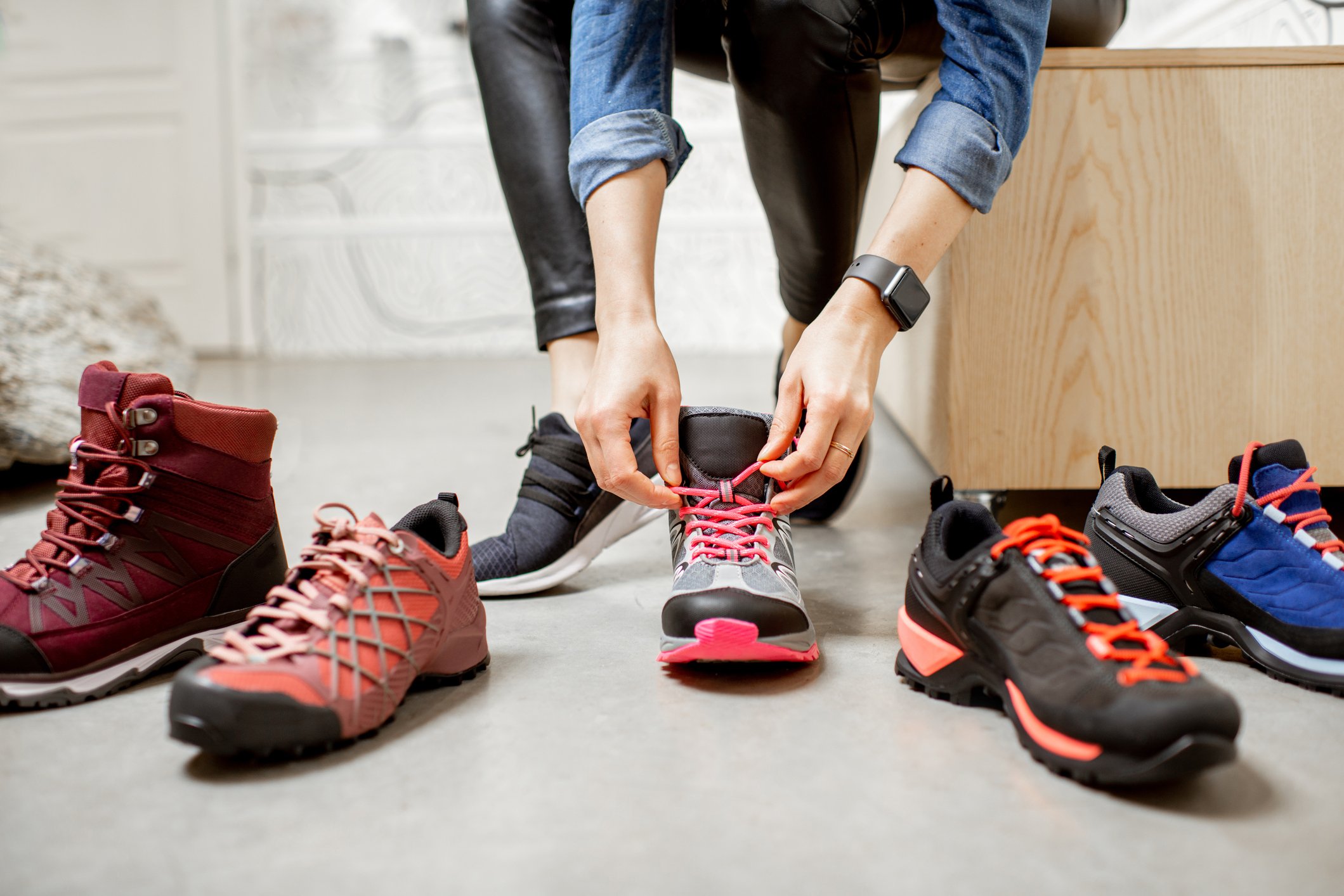 A person holds the laces of a shoe that sits between several other athletic shoes.