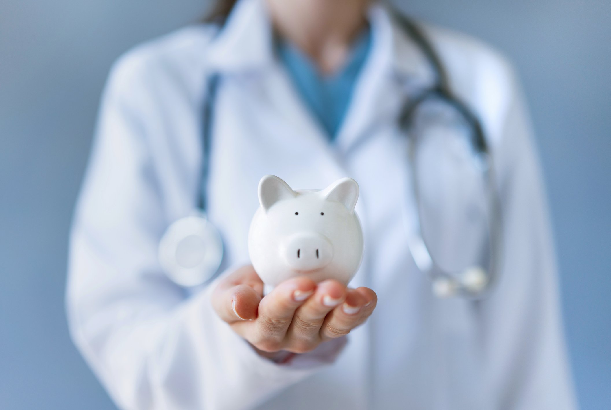 Female doctor holding a piggy bank.