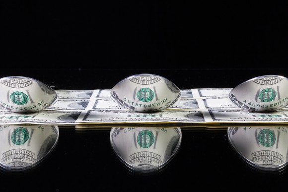 Money reflected in stainless steel spoons