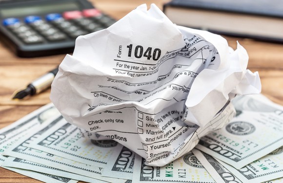 Crumpled tax form with money calculator-and notepad.