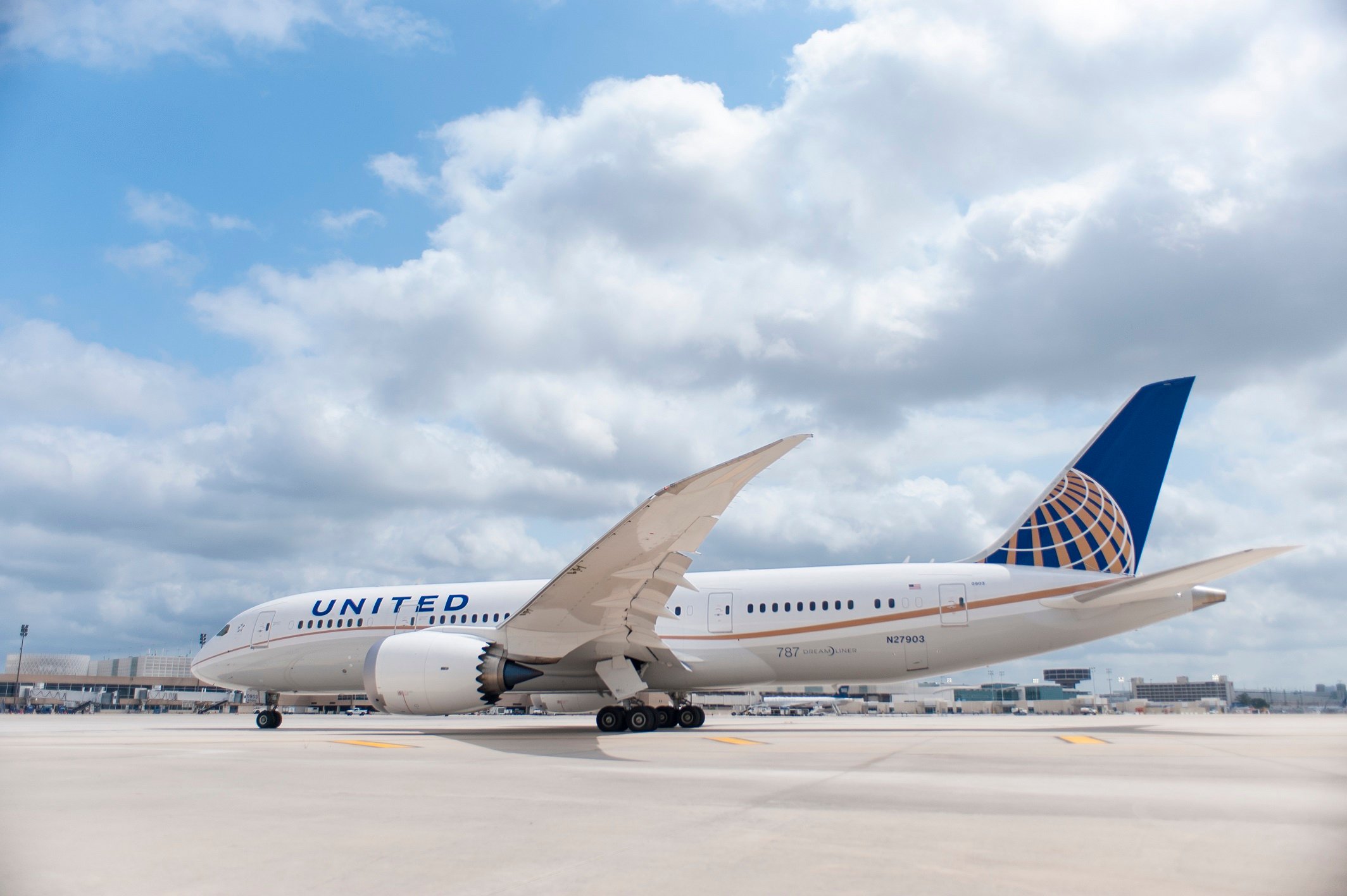 United jet on the runway under a mostly cloudy sky.
