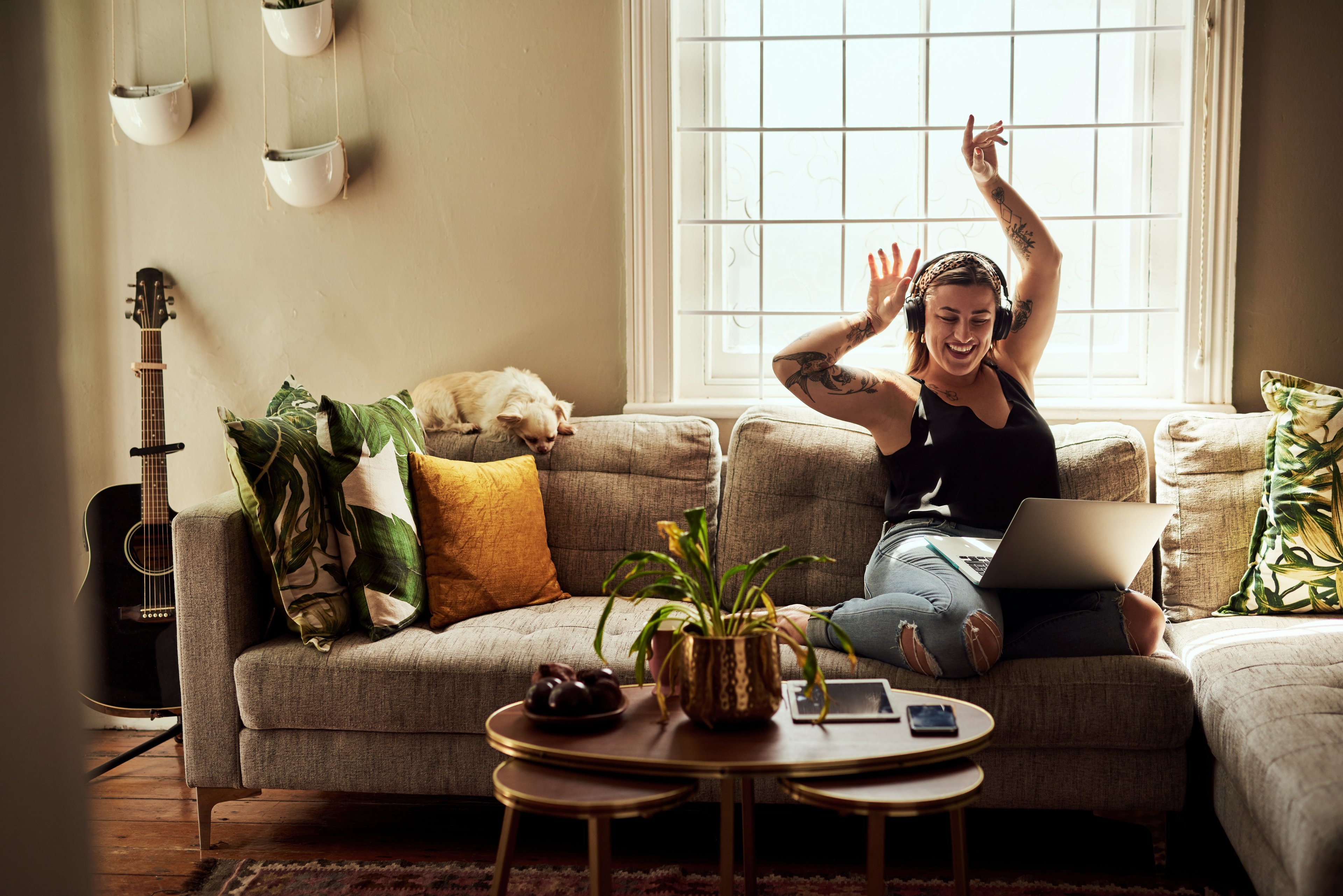 A woman in her living room listening to music from her computer. 