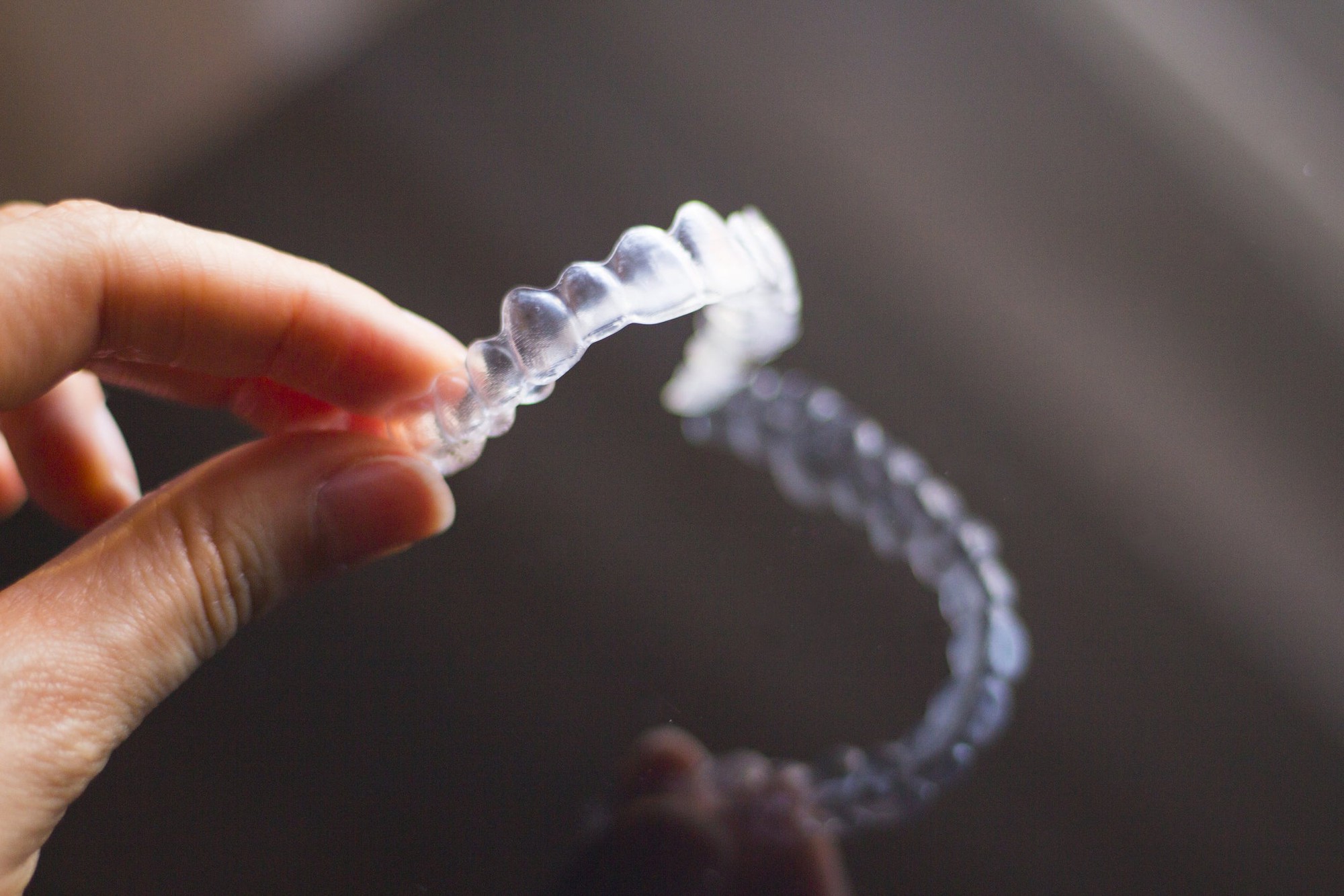 A hand holding clear teeth aligners.