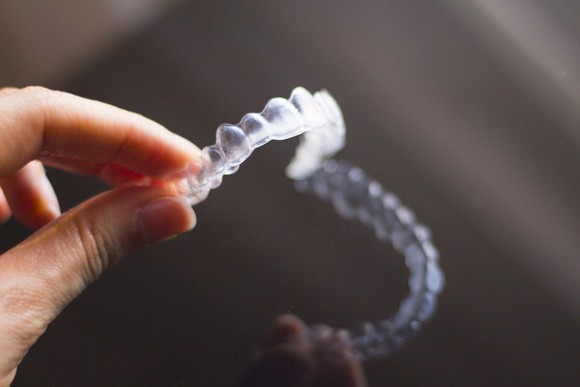 A hand holding clear teeth aligners.