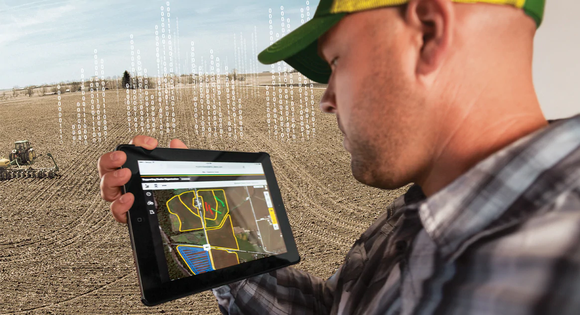 A farmer using Deere's telematics to remotely guide equipment.