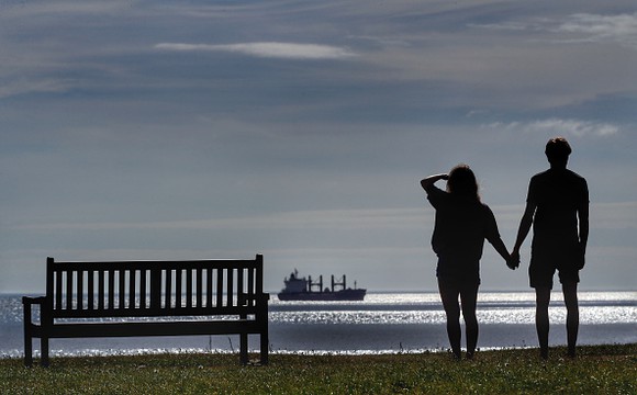 Couple holding hands looking out at a horizon. 