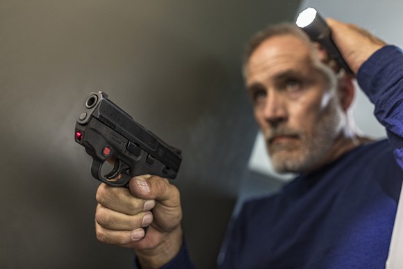 Man with laser-sighted pistol and flashlight
