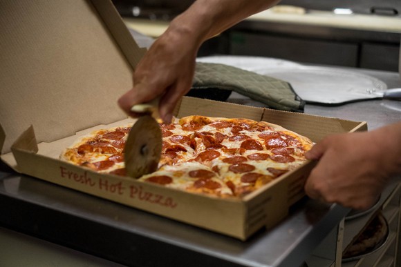 worker slicing pizza just out of the oven