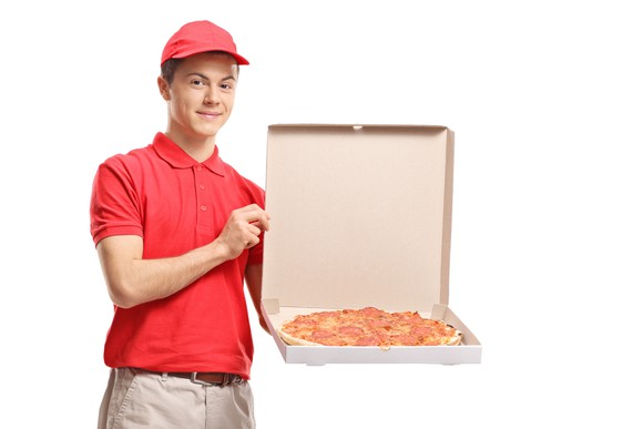 Pizza delivery boy with a red shirt and red cap holding an open pizza delivery box.