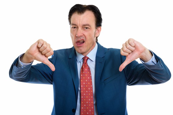 Man in suit giving two thumbs down sign.