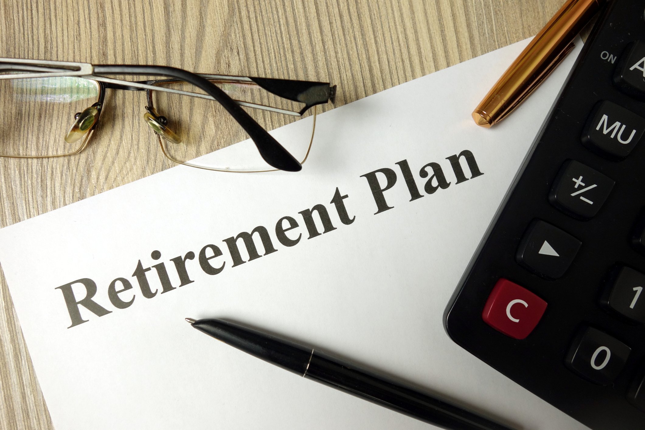 Glasses, pen, and calculator on desk with a written retirement plan.