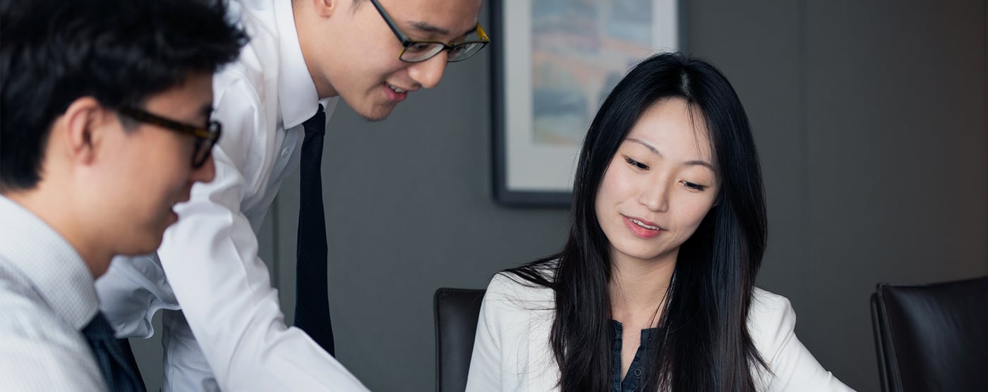 Two men in business suits conferring with a woman.