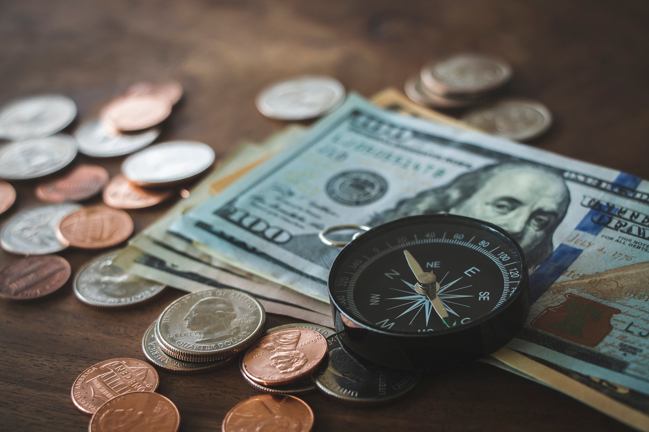A compass on top of cash and coins.