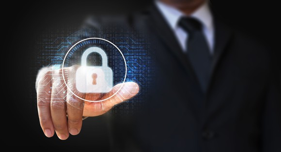 A person in a business suit is pointing to a digital image of a lock.