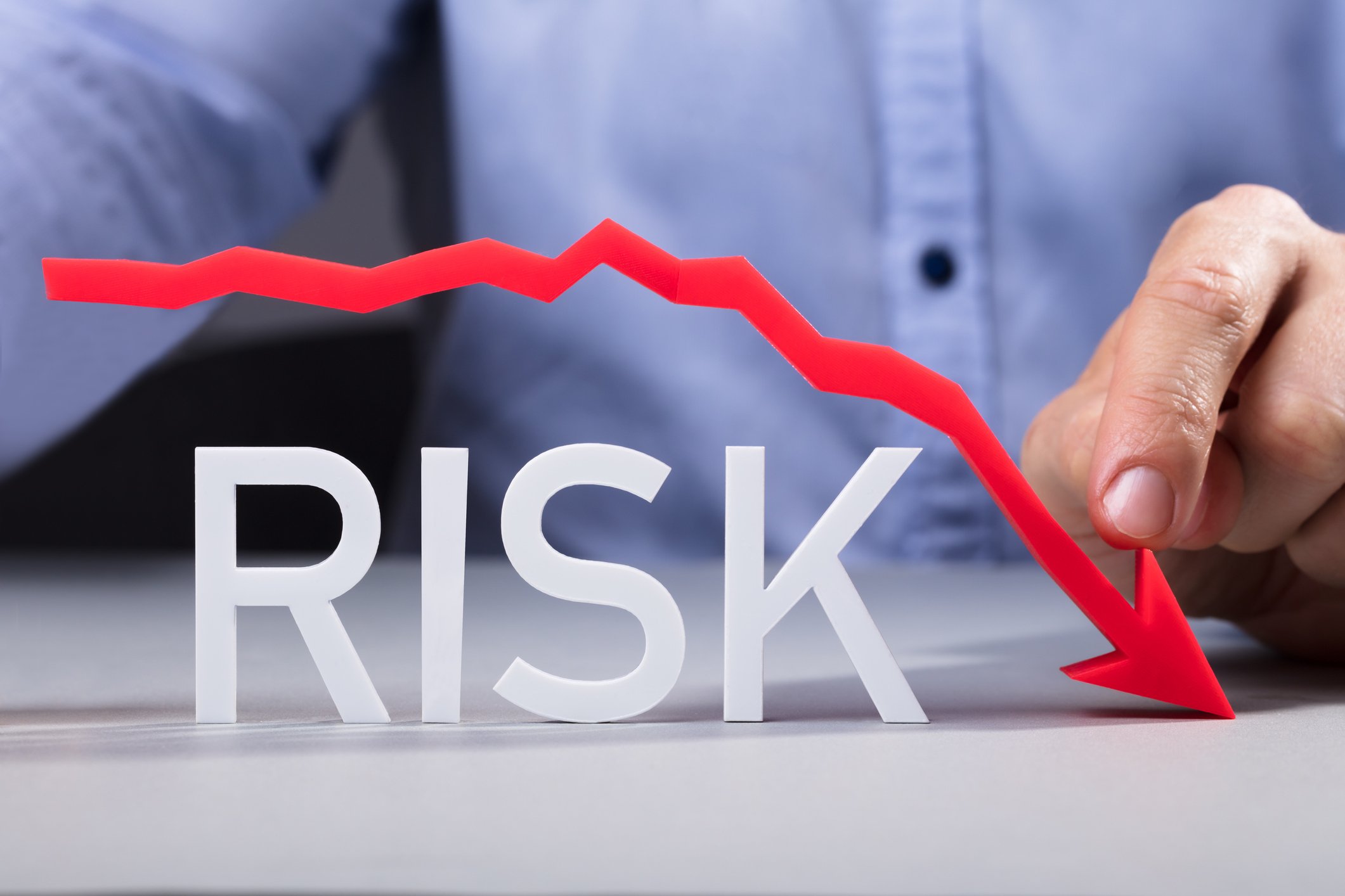 The word Risk with a red line over it, trending downward, and a man in the background