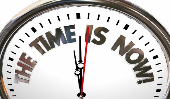 A clock displays the words the time is now.