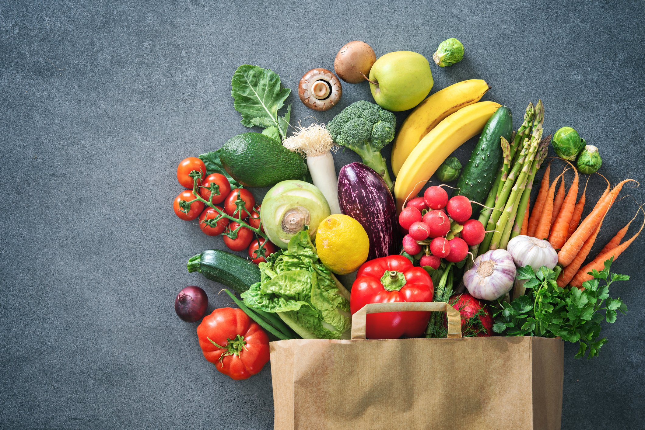 A full brown bag displays an assortment of fresh produce.