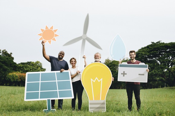A group of people holding up cutouts of various renewable energy symbols.