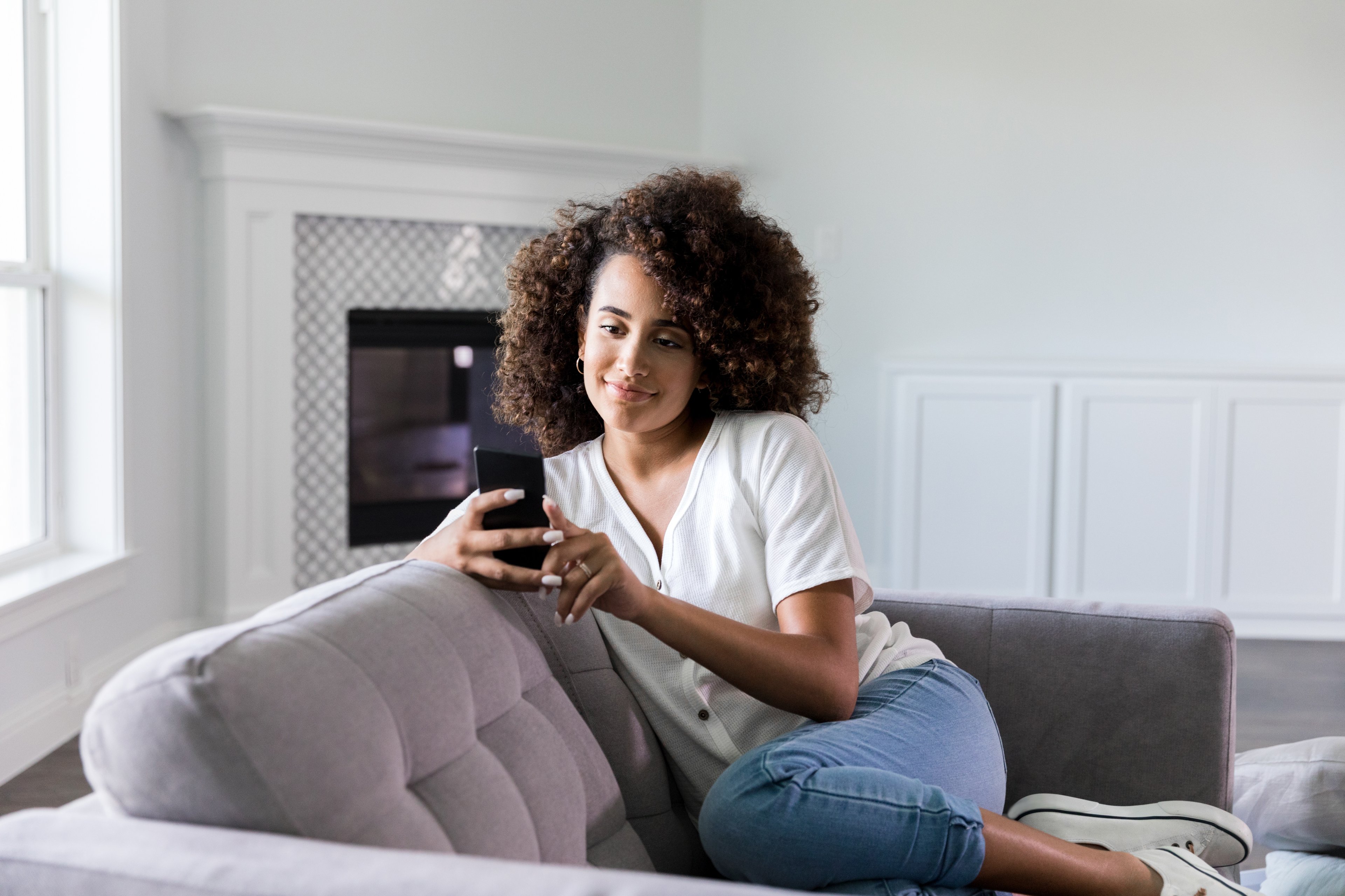 A woman on her couch playing a mobile game. 