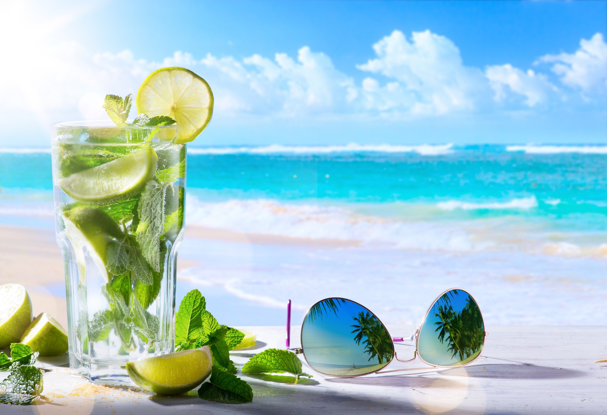 Sunglasses and a glass in front of ocean.