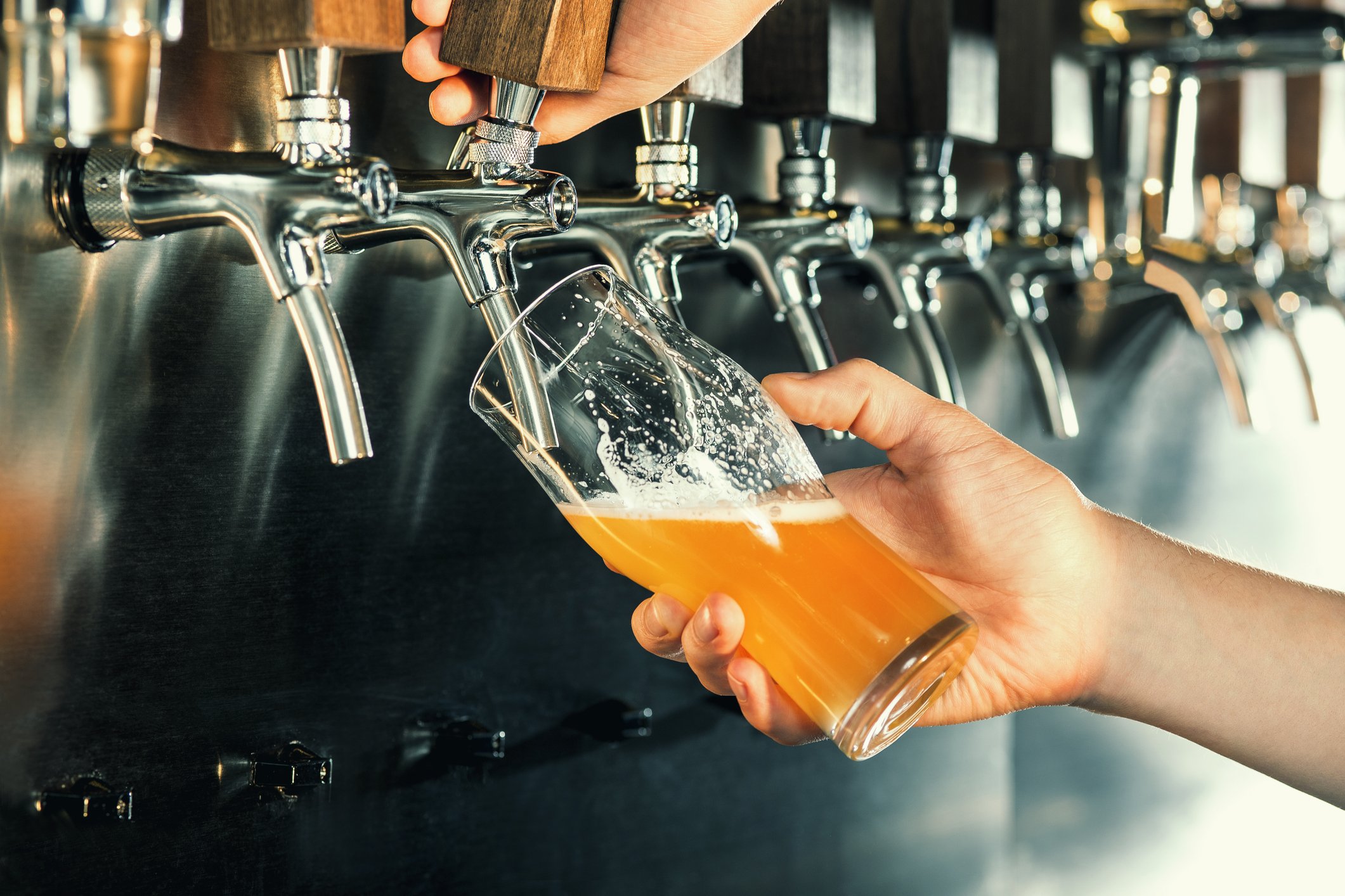 A person fills a beer glass from a tap