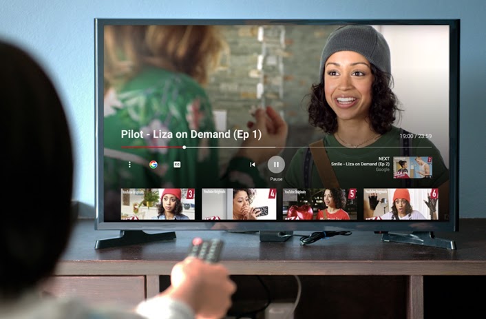 A person pointing a remote at a TV displaying YouTube videos.
