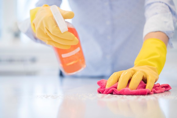 A person disinfects their counter with cleaning spray.