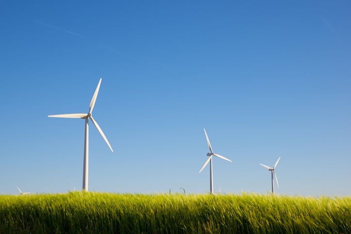 A row of wind turbines in a grassy field.