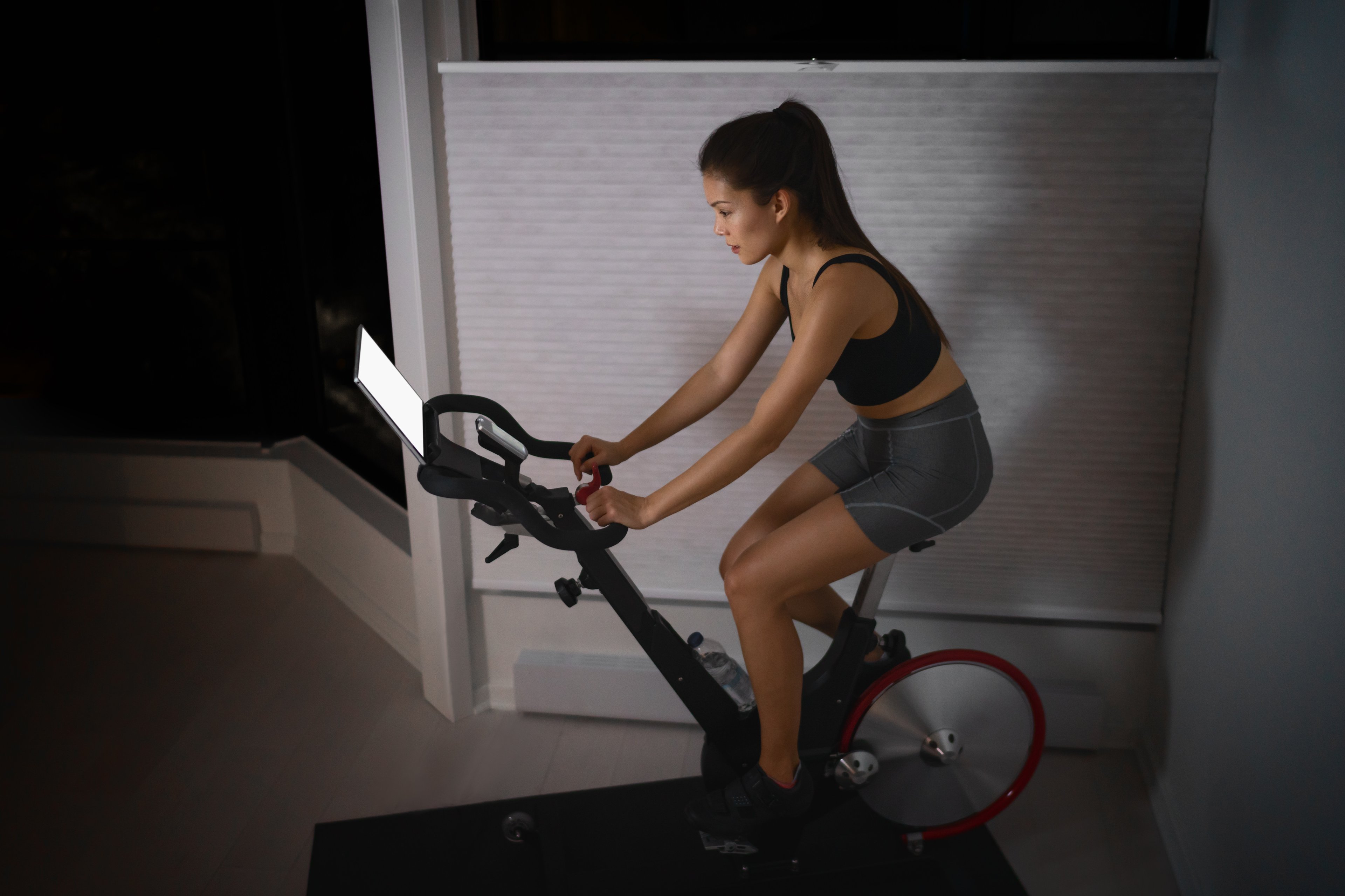 A woman on a exercise bike watching the digital screen. 