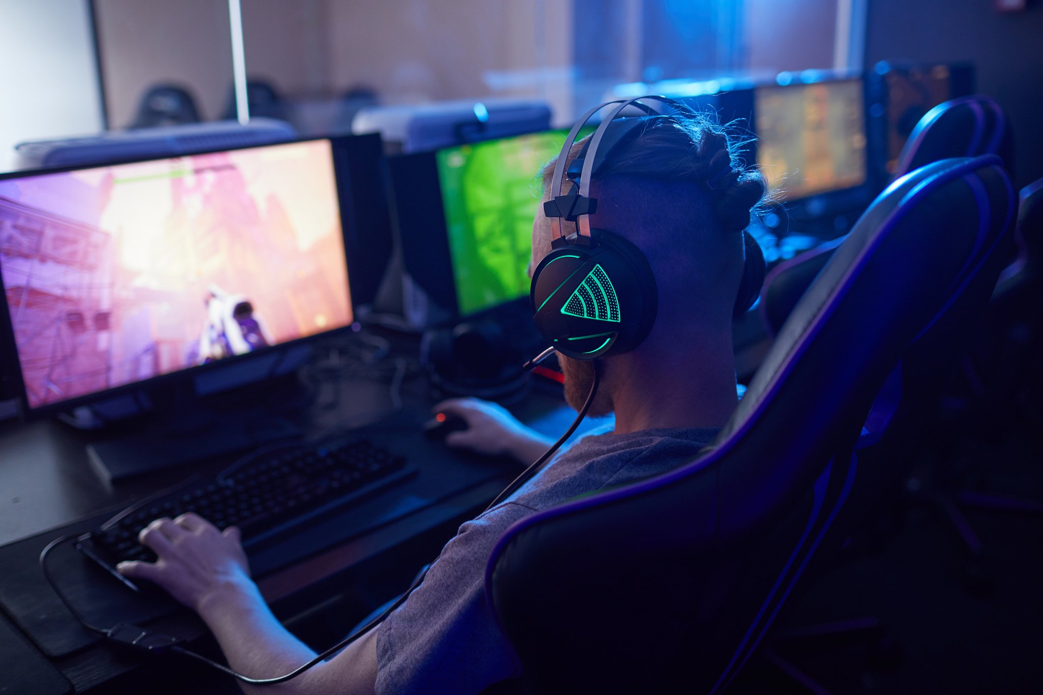 Gamer wearing headphones while he plays a game on his PC.