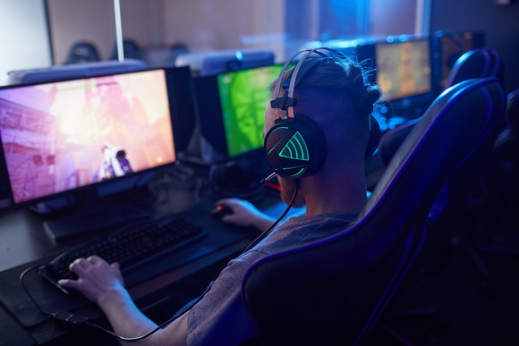 Gamer wearing headphones while he plays a game on his PC.