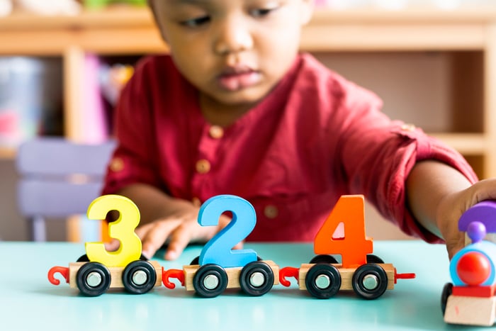 A toddler playing with a number wood toy in a daycare setting. 