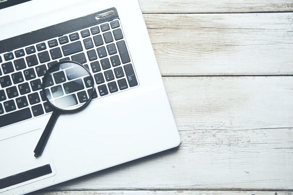 A magnifying glass and a laptop.