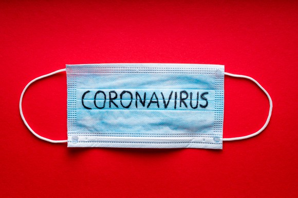 A mask with coronavirus written on it is shown against a red background.