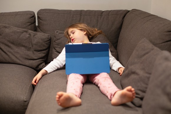Young girl with computer asleep on a modular couch.