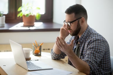 Frustrated man on phone at laptop